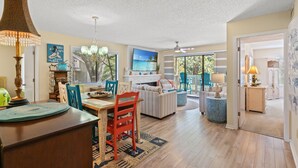 A spacious living room with a dining area, a fireplace, and a large window with a view of the outdoors. - W Hyde Pk 19A in Kingston 1st floor, Pool, Beach (Myrtle Beach)