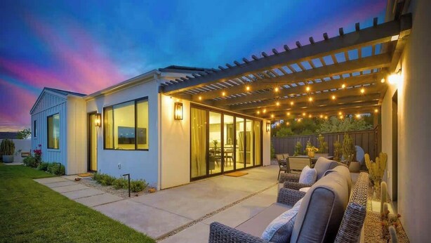 A modern house with a covered patio, outdoor seating, and a well-lit entrance. - Private Cardiff Beach House (Encinitas)