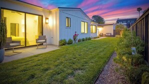 A modern house with a well-maintained lawn, large windows, and outdoor seating. - Private Cardiff Beach House (Encinitas)