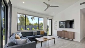 A modern living room with a grey sofa, a wooden coffee table, and a TV mounted on the wall. - Private Cardiff Beach House (Encinitas)