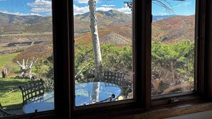 Una habitación con un ventanal grande que da a un paisaje pintoresco con colinas y árboles.
