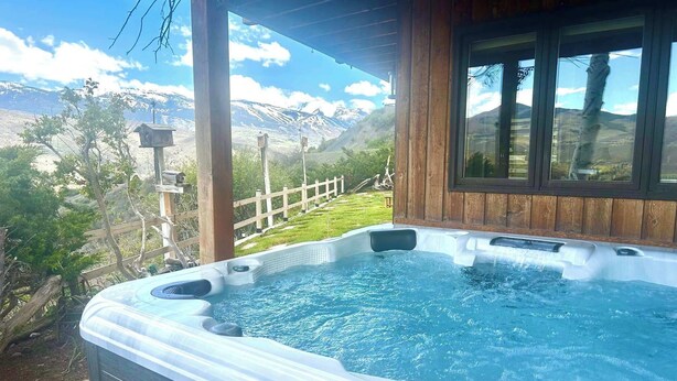 Un jacuzzi con terraza de madera y vistas a montañas.
