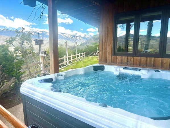 A hot tub with a wooden deck and a view of mountains.