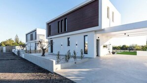 Een modern huis met twee verdiepingen, een plat dak, grote ramen en een minimalistisch ontwerp.