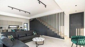 Een moderne woonkamer met een grijze bank, een ronde salontafel en een groene fauteuil.