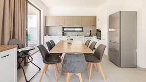 Een moderne keuken met een eettafel, stoelen en een koelkast.