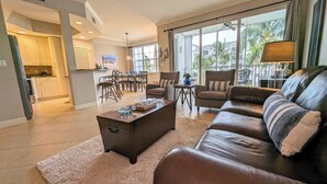 A spacious living room with a leather sofa, a coffee table, and a dining area with chairs and a table.