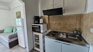 Une cuisine de taille réduite équipée d’un four à micro-ondes, d’une cuisinière et de placards.