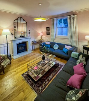 A living room with a fireplace, a sofa, a coffee table, and a window with curtains. - Luxury Cottage in the Heart of Bath (Bath)