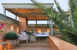 A covered outdoor seating area with a table and chairs, surrounded by plants and a decorative ceiling. - Magnificent Riad in Midina With Swimming Pool (Marrakech)