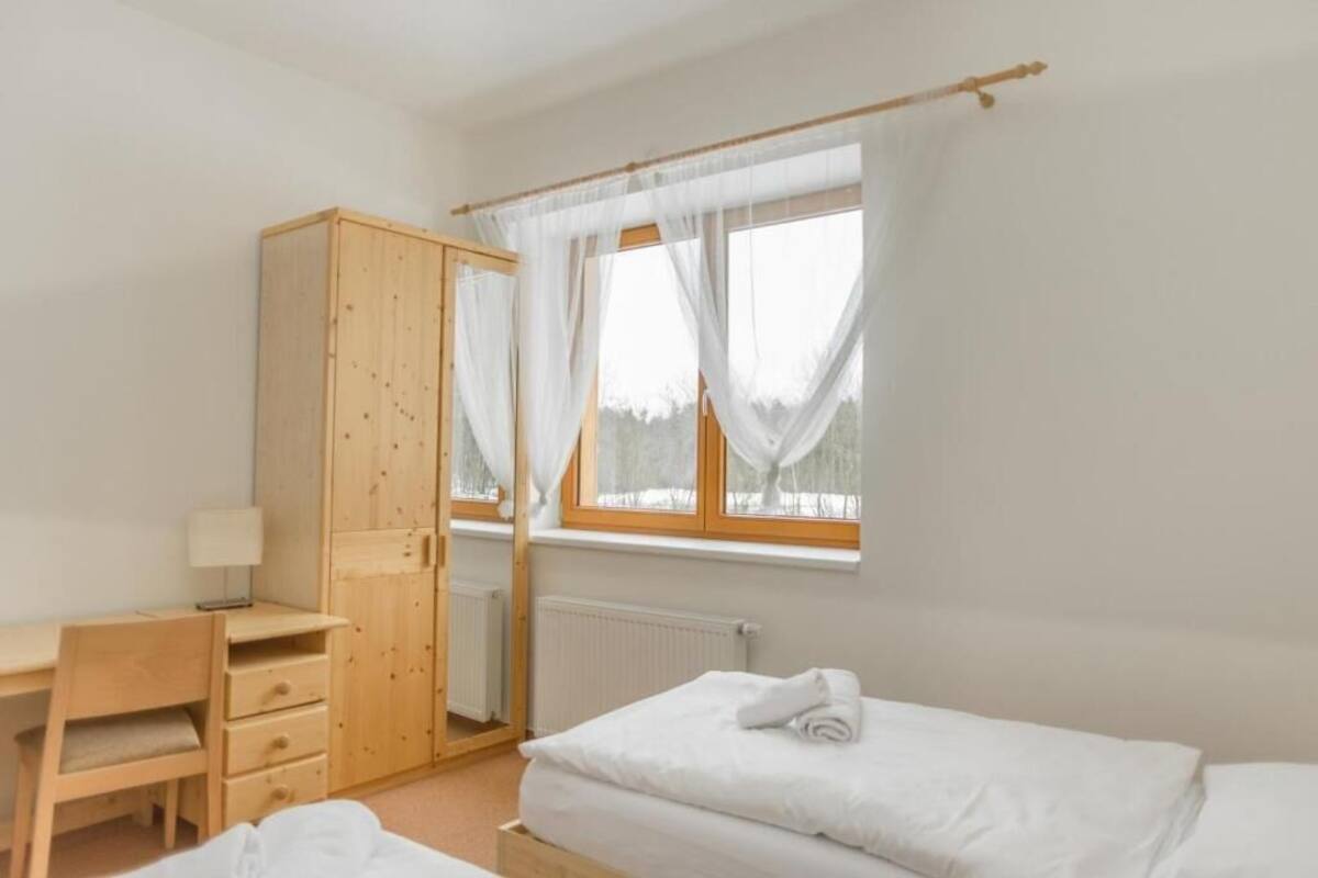 Une chambre avec une armoire en bois, un bureau avec une lampe et un lit avec une literie blanche.
