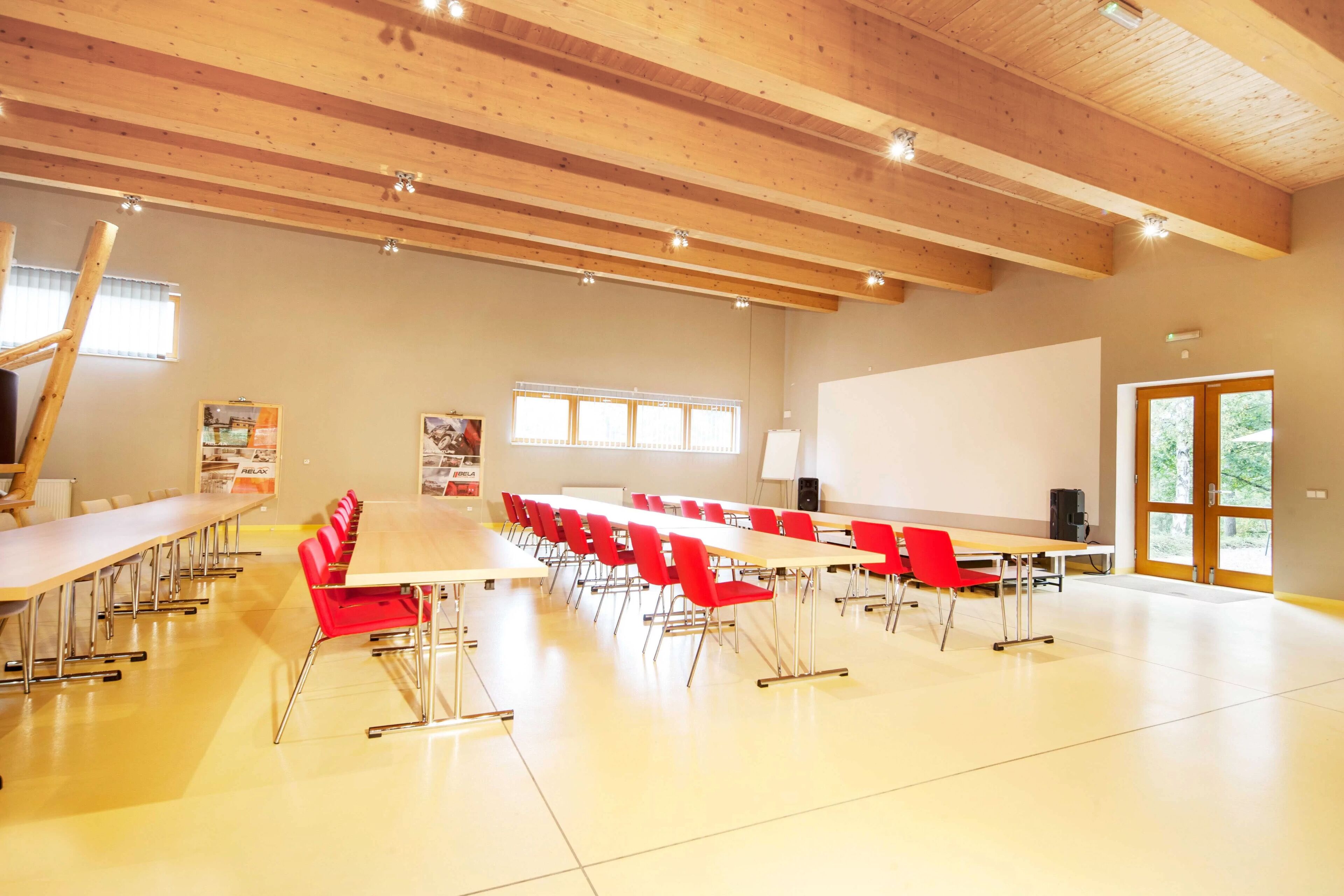 A conference room with a long table, red chairs, a whiteboard, and a projector screen.