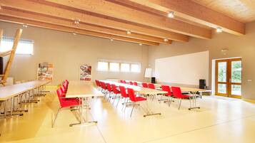 A conference room with a long table, red chairs, a whiteboard, and a projector screen.
