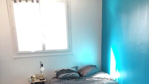 A bedroom with a bed, a nightstand, a lamp, and a window. - House rental for 24h of Le Mans, Le Mans Classic and Grand Prix events (Parigné-l'Évêque)
