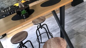 A modern kitchen with wooden cabinets, a black countertop, and a central island with stools. - House rental for 24h of Le Mans, Le Mans Classic and Grand Prix events (Parigné-l'Évêque)