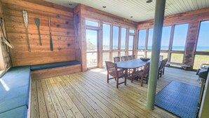 Une terrasse en bois avec une table et des chaises, donnant sur une plage.