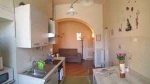A compact kitchen with white cabinets, a sink, and a dining area with a table and chairs. - Casa Tua a Porta Maggiore (Rome)