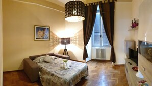 A bedroom with a bed, a sofa, a lamp, a radiator, and a TV. - Casa Tua a Porta Maggiore (Rome)