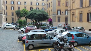 A parking lot with multiple cars and motorcycles, surrounded by buildings with classic architecture. - Casa Tua a Porta Maggiore (Rome)