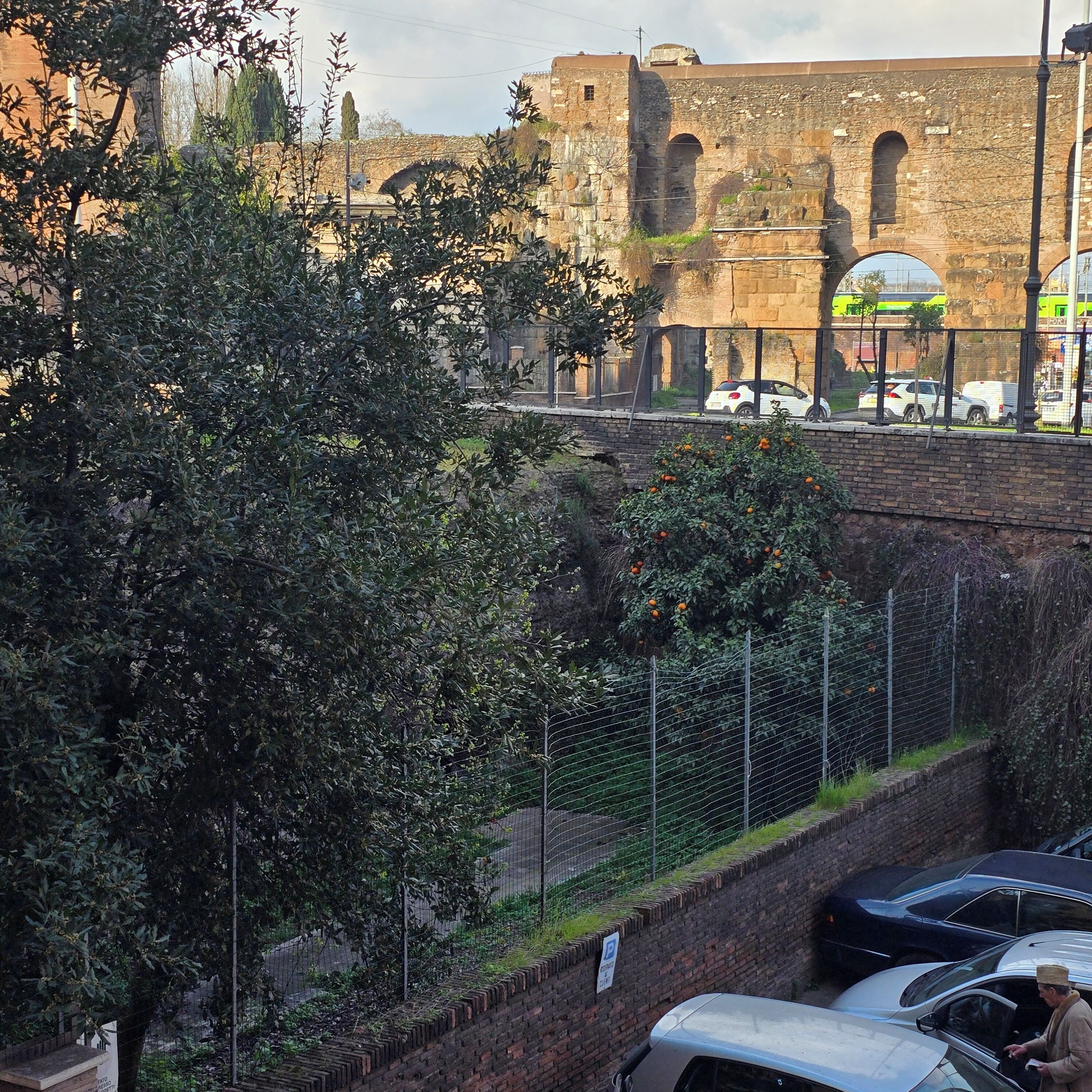 A view of a historic stone building with arched windows and a brick wall.