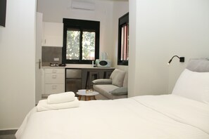 Una habitación compacta con cama, kitchenette y una pequeña zona de estar.