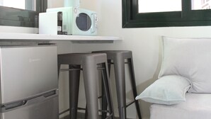 A compact kitchen with a refrigerator, a microwave, and a window with a view of the outside. - Pirgos Warm Studio for 3 by MPS (Pirgos)