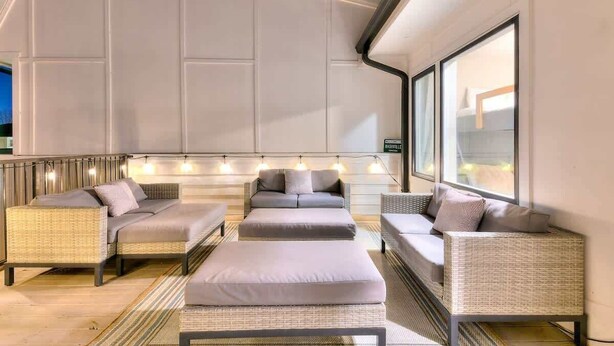 A modern living room with wicker furniture, a large window, and a ceiling with recessed lighting. - Bright and Spacious 4 Bedroom Nash Home w/Rooftop! (Nashville)