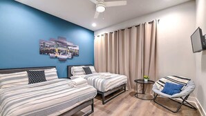A bedroom with two beds, a chair, a TV, and a ceiling fan. - Bright and Spacious 4 Bedroom Nash Home w/Rooftop! (Nashville)