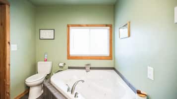 A bathroom with a toilet, a bathtub, and a window.