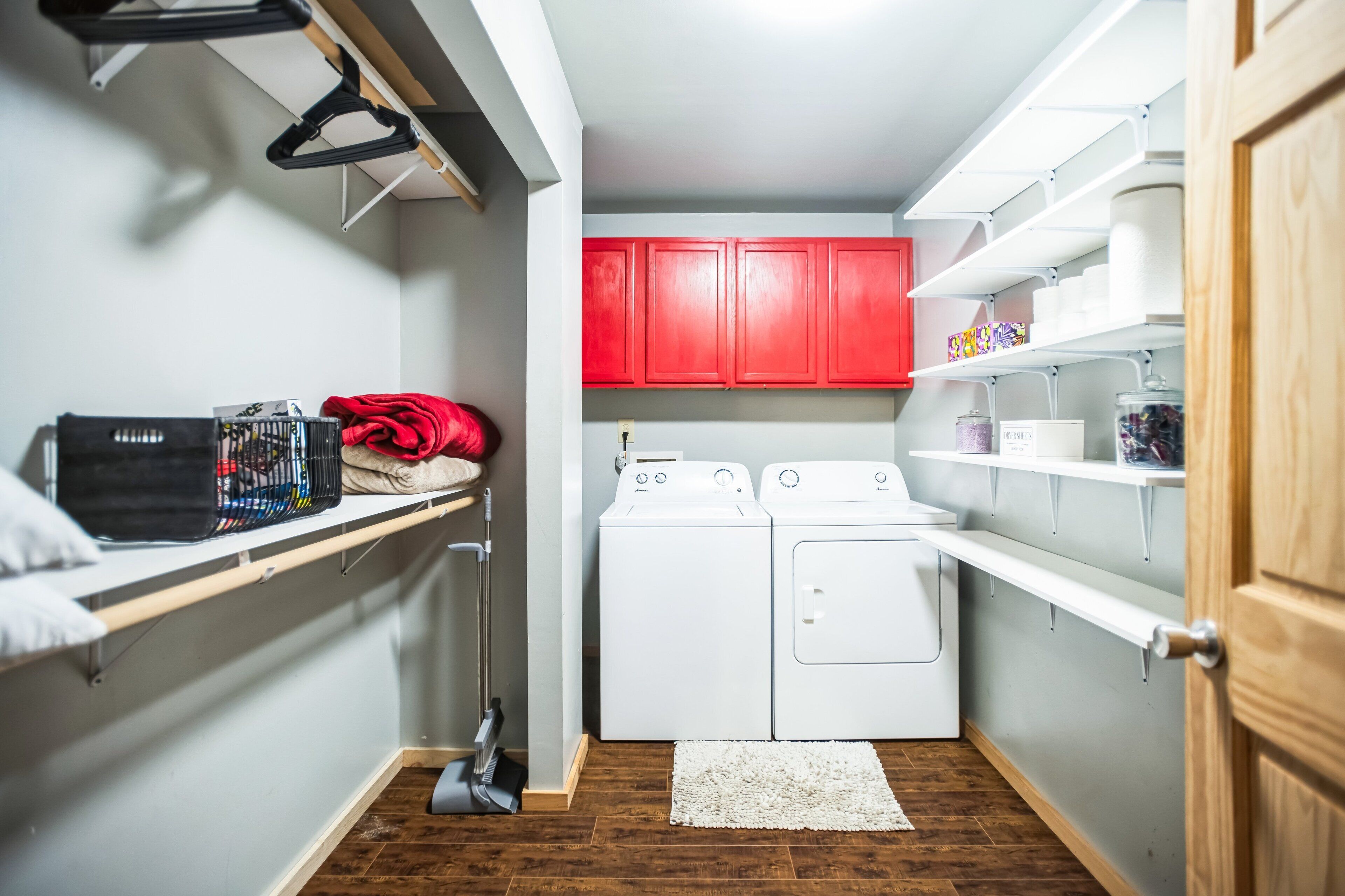 A laundry room with two washing machines, a drying rack, and shelves with laundry supplies.