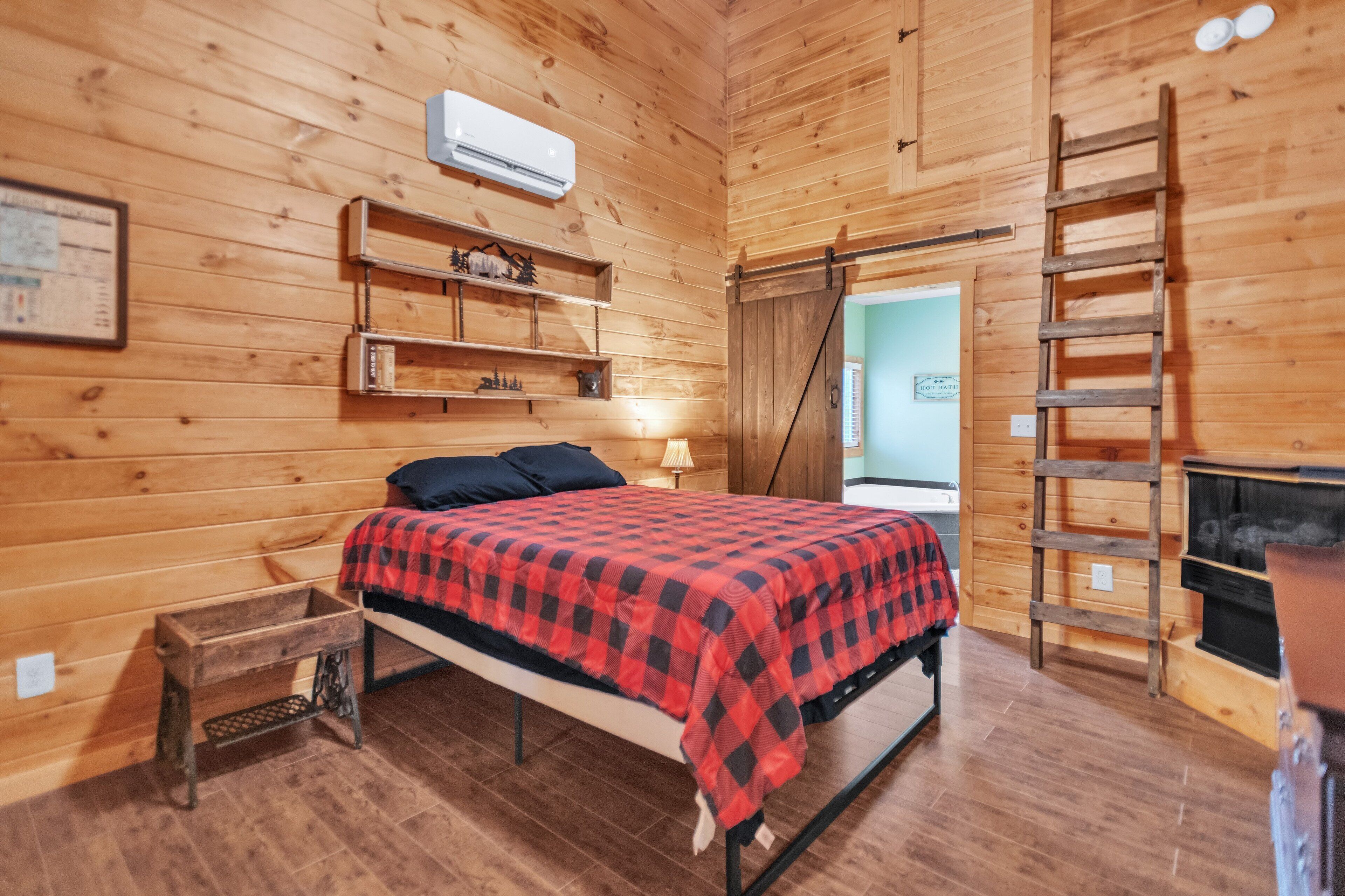 Une chambre confortable dans un chalet en bois, avec un lit, des étagères, une échelle et une cheminée.