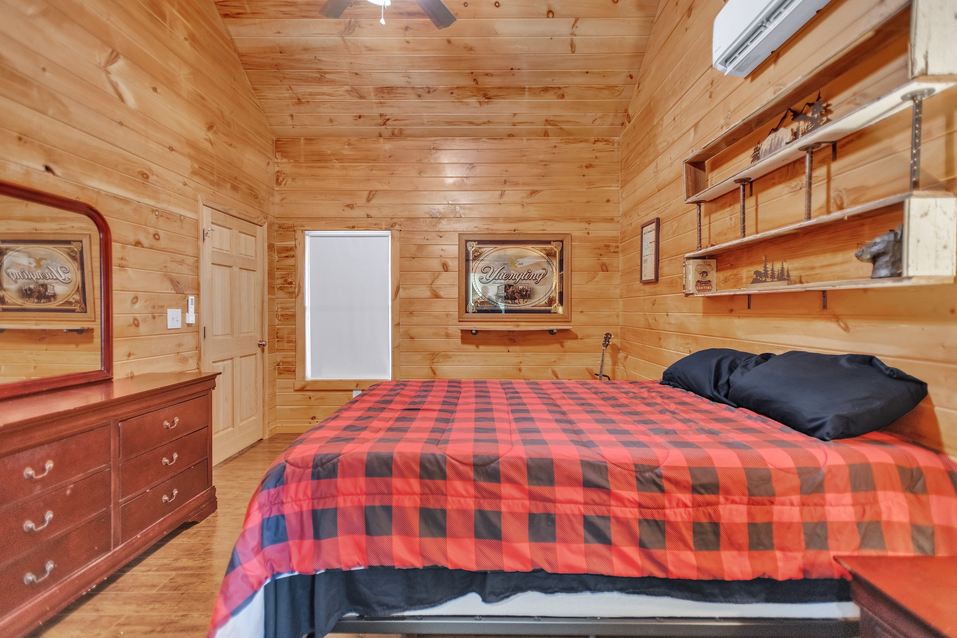 A wooden-paneled room with a bed, dresser, and shelves with decorative items.