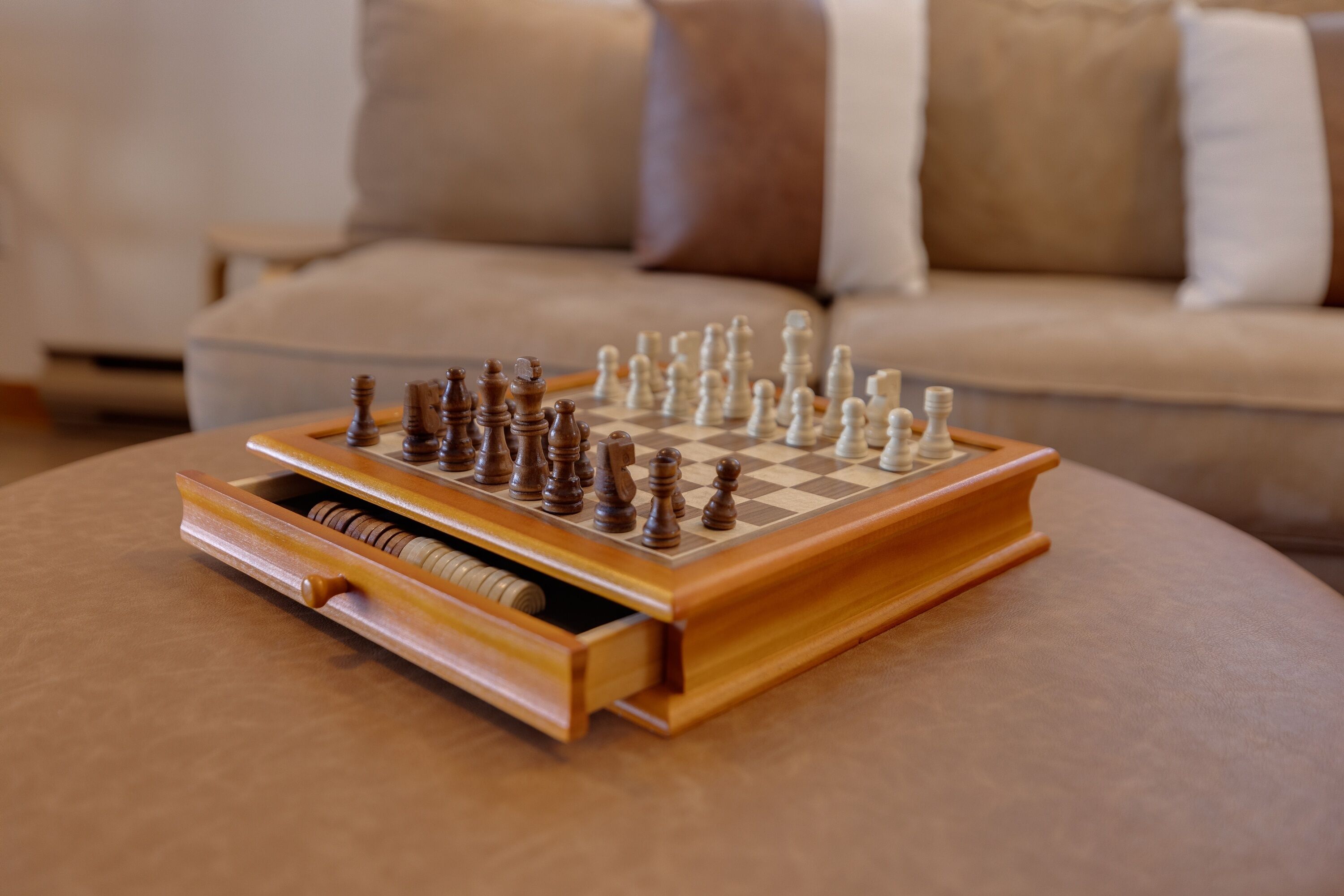 A chessboard on a wooden table with a sofa in the background.