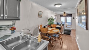 A modern kitchen with a double sink, wooden dining table, and chairs. There is a window with blinds and a ceiling fan. - Beautiful Lakeview Chateau With Stunning Views 3 Bedroom Home (Rutledge)