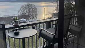 A balcony with a table and chairs, overlooking a body of water and distant mountains. - Beautiful Lakeview Chateau With Stunning Views 3 Bedroom Home (Rutledge)