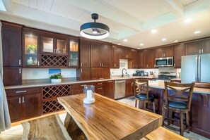 A modern kitchen with wooden cabinets, a central island, and a dining area with chairs.