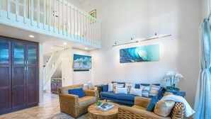 A spacious living room with a high ceiling, a staircase, and a large window. - Puamana at Princeville Island Style Townhome, Beautifully Updated, sleeps 8 (Princeville)