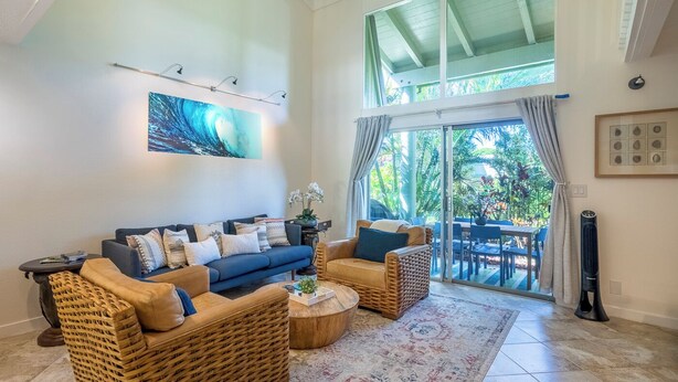 A spacious living room with a large sofa, two armchairs, a coffee table, and a dining area with a table and chairs. - Puamana at Princeville Island Style Townhome, Beautifully Updated, sleeps 8 (Princeville)