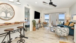 Un salon moderne doté d’un bar en bois, d’un ventilateur de plafond et offrant une vue sur l’extérieur.