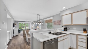 A modern kitchen with white cabinetry, a dishwasher, and a large island with a sink. - 11d True Blue Golf Haven Ii 2 Bedroom Home (Pawleys Island)