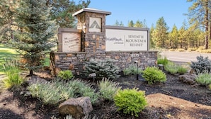 A stone sign with 'SEVENTH MOUNTAIN RESORT' and 'THE OUTFITTER BAR' for a resort. - Seventh Mt 1417/1418 1 Bedroom Condo (Bend)