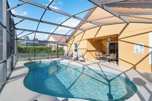 Ein Schwimmbad mit Glasverkleidung, Sitzgelegenheiten im Freien und freiem Blick zum Himmel.