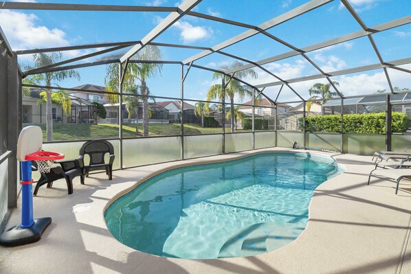 Ein überdachter Pool mit Basketballkorb, Liegestühlen und Blick auf die Umgebung.