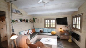 Une chambre confortable, aménagée dans le style d’un chalet, avec un canapé-lit, une table basse et un téléviseur.