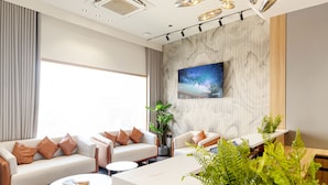 Un salon moderne avec deux canapés, une table basse et un téléviseur fixé au mur, qui est recouvert de marbre.