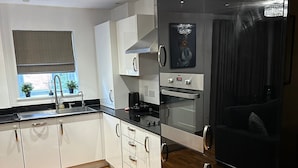 Una cocina moderna con armarios blancos, un refrigerador negro y piso de madera.