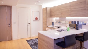 Une cuisine moderne avec des meubles en bois, un plan de travail blanc et un four encastré.
