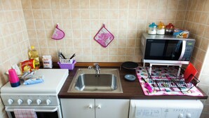 A compact kitchen with a sink, stove, microwave, and washing machine. - Casa Tua sul tetto di Roma (Rome)