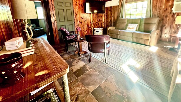 Ein gemütliches Blockhaus-Interieur mit Holzbalkendecke, einer Couch, einem Tisch und einem Fernseher.