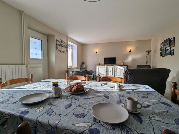 A dining area with a table set for two, a television on a cabinet, and a window with blinds. - Charming Cottage for 6 with Terrace and Wifi (Raucoules)